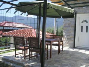 una mesa y sillas bajo una sombrilla en un patio en Villa Pegasos, en Chrysi Ammoudia