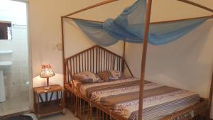 a bedroom with a canopy bed with a lamp on a table at La Guesthouse Étoile in Cotonou