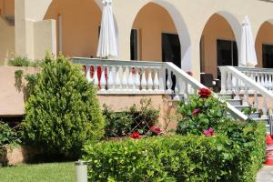 a house with a staircase and flowers and umbrellas at Primavera Hotel in Dassia