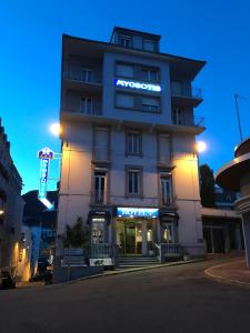 un edificio alto con un letrero de neón. en Hôtel Myosotis en Lourdes