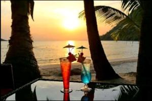 a table with two cocktails on the beach at sunset at vitamin sea villas in Ko Chang