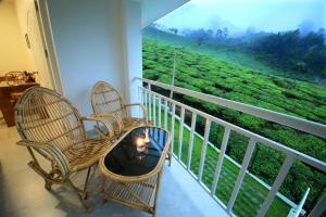 a balcony with two chairs and a view of a tea plantations at Monsoon Grande in Munnar