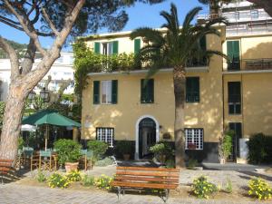 um edifício com uma palmeira e um banco à frente em Hotel Beau Rivage em Alassio