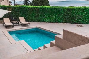 a swimming pool with two chairs and a table at Apartment Serenum in Matulji