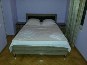 un letto con lenzuola e cuscini bianchi in una camera da letto di Guesthouse Kiko a Sighnaghi