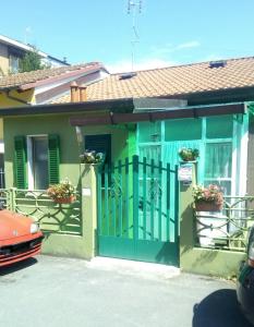 ein grünes Haus mit einem Tor und einem roten Auto in der Unterkunft La Casa di Nonna Videlma in Carrara