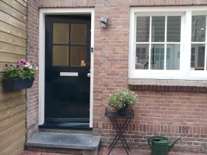 a black door on a brick house with two potted plants at B&B de Notaris in Assen