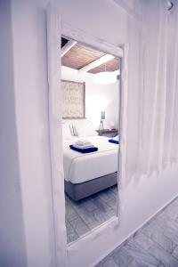 La Playa Boutique Apartments في كاليمنوس: غرفة نوم بيضاء مع سرير ومرآة