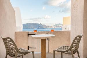 dos copas de vino sentadas en una mesa en un balcón en The Dream Santorini, en Oia