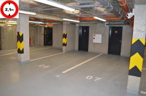 an empty parking garage with yellow and black arrows on columns at Residence Trafick in Prague
