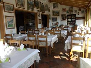 jadalnia z białymi stołami i krzesłami w restauracji w obiekcie Al Fogolar w mieście Villa Santina +37 zdjęć