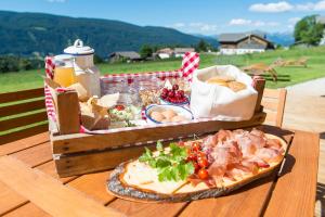 una cesta de picnic llena de comida en una mesa de madera en Mair am Graben Farm * Chalets, en Terento