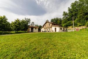 ein altes Haus auf einem Grasfeld vor einem Haus in der Unterkunft Agriturismo Carovane in Compiano