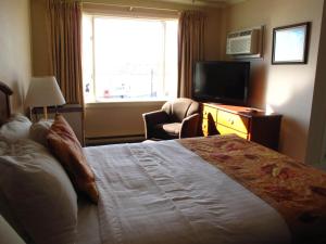 a hotel room with a bed and a television at Brigantine Inn in Lunenburg
