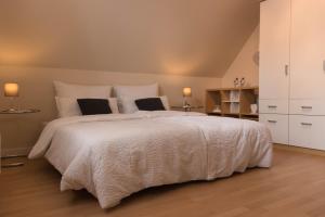 1 dormitorio con 1 cama grande con sábanas y almohadas blancas en Traum-Ferienwohnung-am-See, en Sassenberg