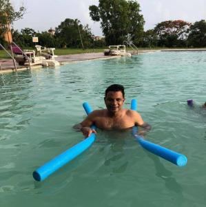 a man in a swimming pool with blue tubes at Veda Vihar Homestay & Yoga Centre in Cochin
