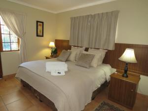 una camera da letto con un grande letto bianco con due cuscini di Butterscotch B&B a Pinetown