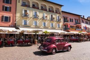 een oude rode auto geparkeerd voor een gebouw bij Piazza Ascona Hotel & Restaurants in Ascona