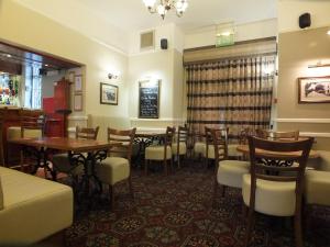 a restaurant with tables and chairs and a bar at Eskdale Lodge in Sale