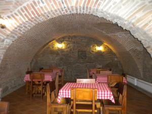 シギショアラにあるPensiunea Bastionのレンガの壁にテーブルと椅子が並ぶレストラン