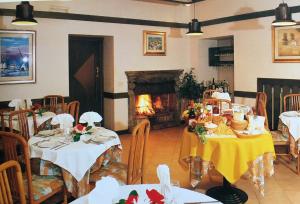 uma sala de jantar com mesas e uma lareira em Cristall Hotel em Rocca di Cambio