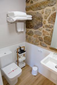 a bathroom with a white toilet and a stone wall at A Bughina apartamentos in Muxia