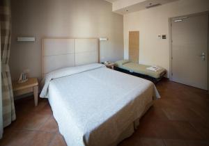 a bedroom with a large white bed and a door at Hotel Miramare in Castiglione della Pescaia