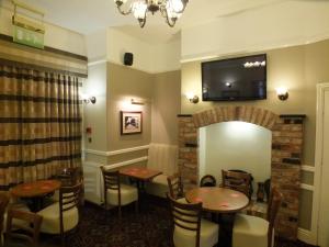 a restaurant with tables and chairs and a television on the wall at Eskdale Lodge in Sale