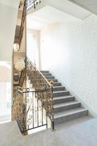 un escalier dans une maison avec une balustrade en fer forgé dans l'établissement Hôtel d'Angleterre (by Popinns), à Vittel