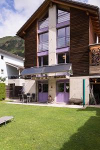 a house with purple doors and a grass yard at B&B Gottardo in Airolo