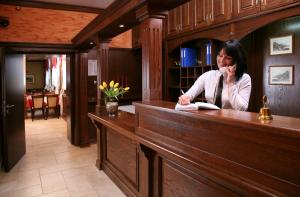 a woman sitting at a desk writing in a book at Willa Koba in Ustroń