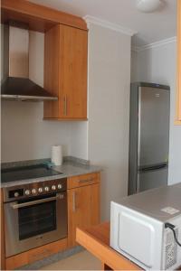 a kitchen with a stove and a refrigerator at Mi piso en la ría in Barreiros