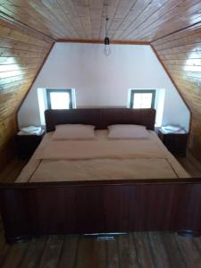 a large bed in a wooden room with two windows at Bujtina Ahmetaj in Valbonë