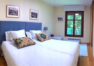 1 dormitorio con 1 cama blanca grande con almohadas en Apartamentos Venuntiempo, en Llanes