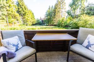 dwa krzesła i stół na ganku w obiekcie Apartment Haus Föhrenwald w mieście Seefeld in Tirol