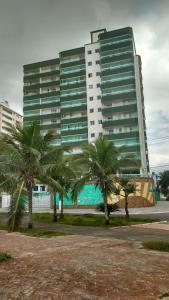 a large building with palm trees in front of it at Apto. (pé na areia) com Churrasqueira na sacada in Praia Grande