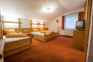 a room with two beds and a television in it at Ferienheim Gasteig in Neustift im Stubaital
