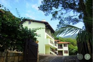 ein weißes Gebäude mit einem Tor davor in der Unterkunft Residencial Caminho das Pedras - Praia da Solidão in Florianópolis