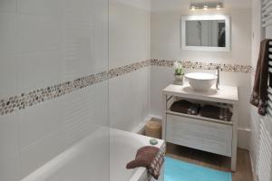 uma casa de banho branca com uma banheira e um lavatório em La Maison au-dessus des Voiles em La Baule