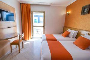 a hotel room with two beds and a table at Zahrat Al Jabal in Fès