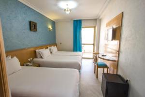 Habitación de hotel con 2 camas, mesa y silla en Zahrat Al Jabal en Fez