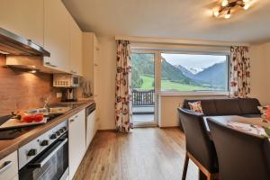 a kitchen with a table and a large window at Aurora Appartements in Neustift im Stubaital