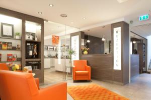 eine Ladenhalle mit orangefarbenen Stühlen und einem Tisch in der Unterkunft Hotel Martinihof in Münster