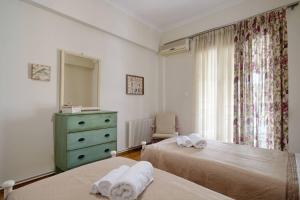 sypialnia z 2 łóżkami, komodą i oknem w obiekcie Caryatis Apartment w Atenach