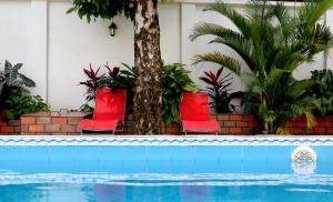 a group of red chairs by a swimming pool at Hotel Jose Antonios Inn in Puerto Maldonado
