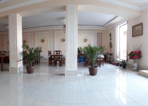 a large room with tables and chairs and potted plants at Hotel Shams in Bukhara