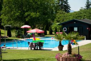 ein Pool mit einem Tisch und Sonnenschirmen sowie ein Haus in der Unterkunft Hotel Zollner in Gödersdorf