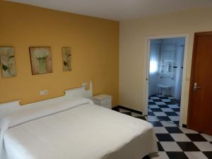 um quarto com uma cama branca e um piso em xadrez em Casa Mariñan em Sanxenxo