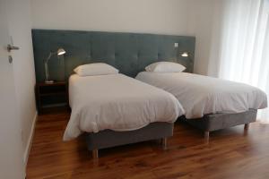 2 camas con sábanas blancas y almohadas en un dormitorio en Guest House Eça - Centro Histórico Leiria en Leiria