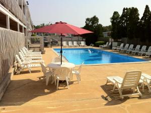 a table and chairs with an umbrella and a pool at Holiday Hill Inn & Suites in Dennis Port